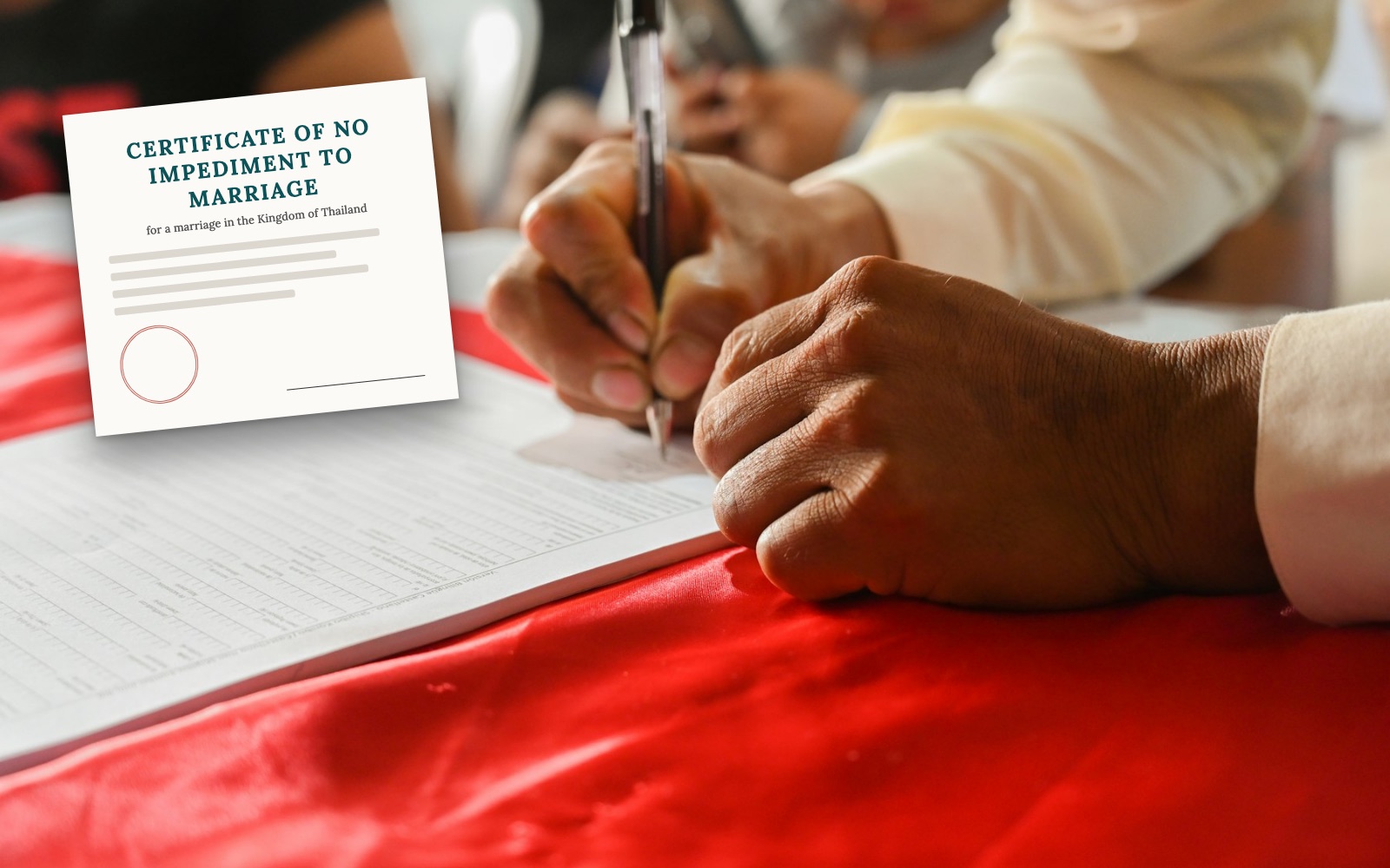 Hands signing a marriage register on a red tablecloth, with a blank certificate of no impediment to marriage